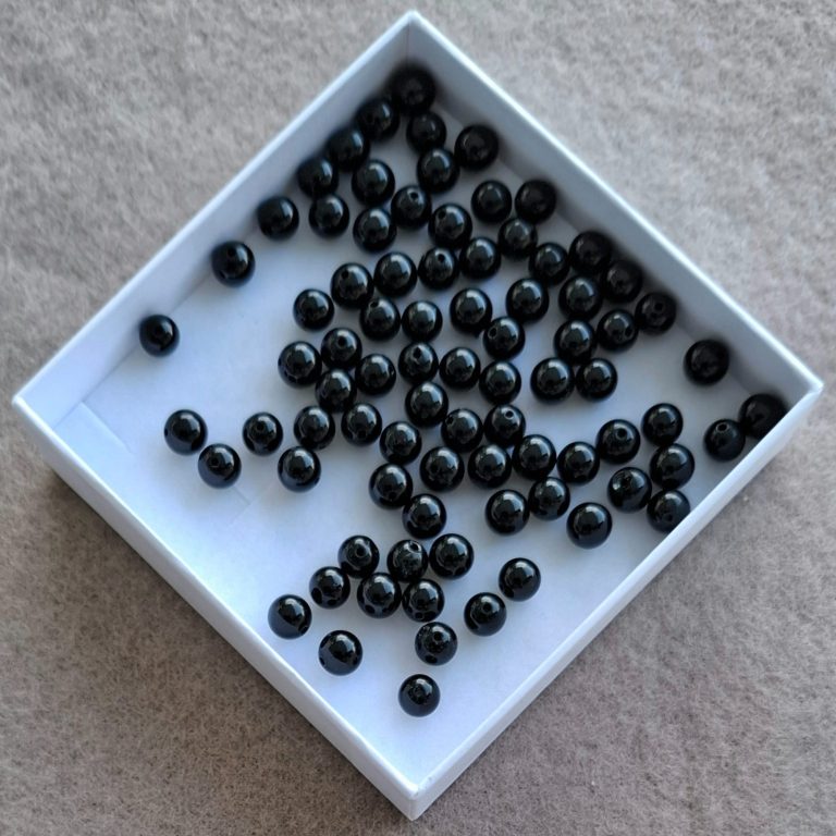 Schwarze Turmalin Perlen Schwarze Perlen in einer weißen Quadratbox.