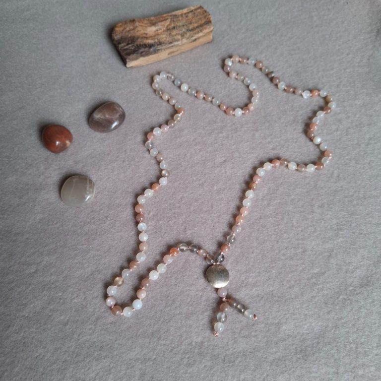 Perlenkette aus verschiedenen Steinen, kombiniert mit drei weiteren Steinen und einem Holzstück.