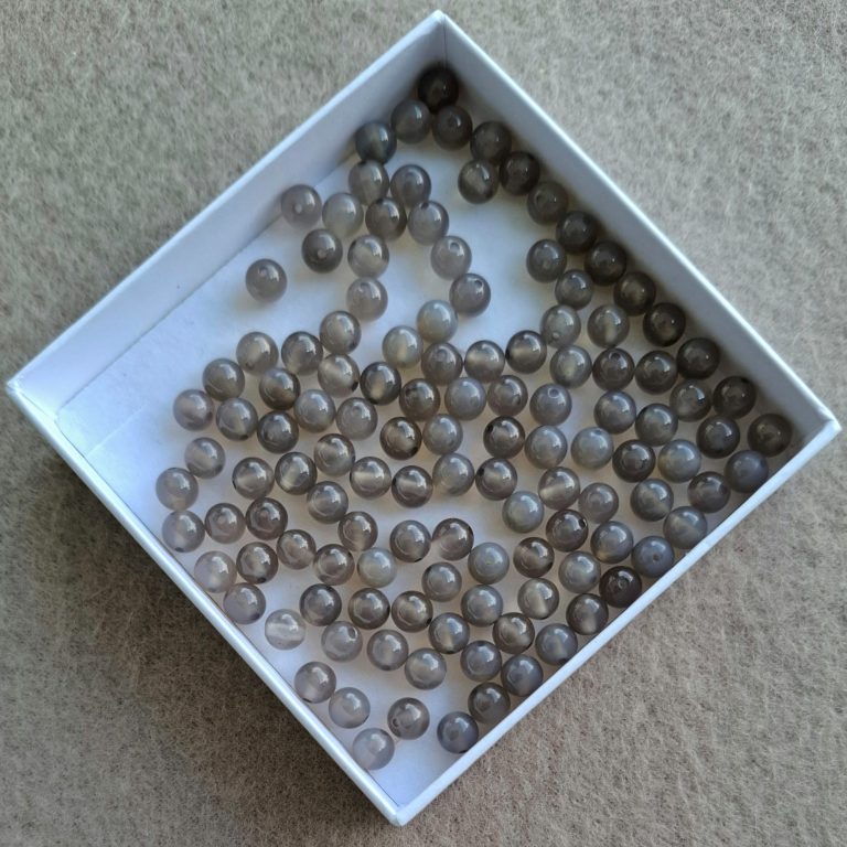 Graue Achat Perlen Ein kleine Schachtel mit vielen kleinen grauen, runden Perlen darin.