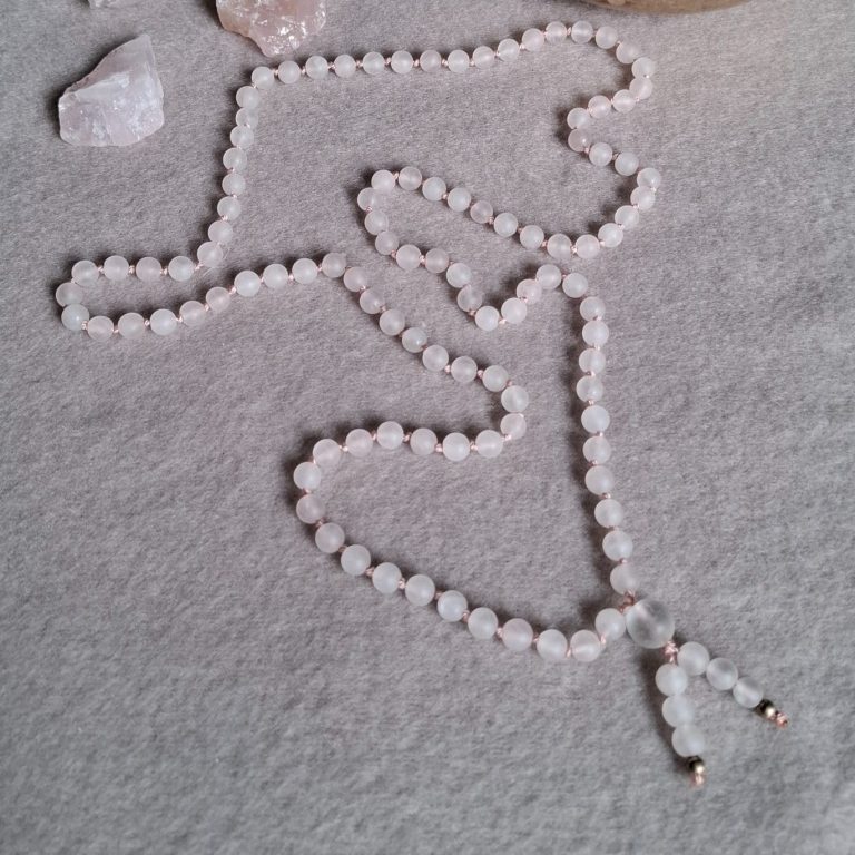 Edelsteinkette aus matten Rosenquarzperlen umgeben von rosa Steinen.