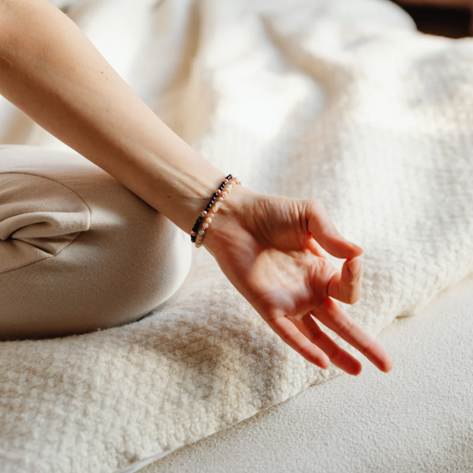 Eine Hand in Meditationshaltung, entspannt auf einer Decke liegend.
