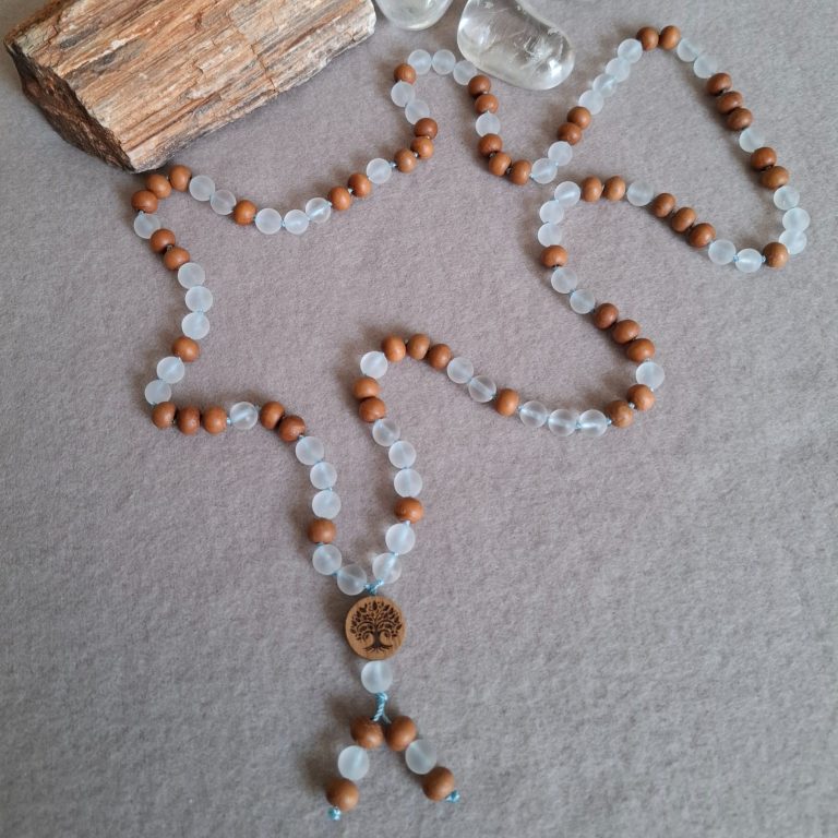 Kette aus braunen Sandelholzperlen und  matten Bergkristall Perlen mit einem Holz-Anhänger in der Mitte.