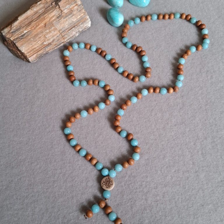 Halskette aus braunen Sandelholzperlen und blauen Amazonit Perlen, neben einem Holzstück.