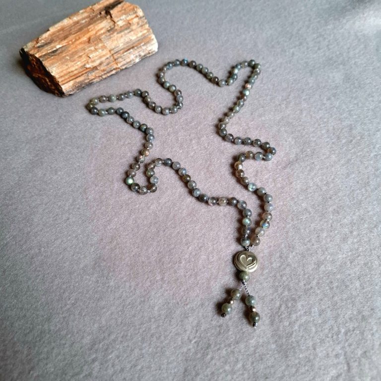 Ein Schmuckstück in Form einer Kette mit einem runden Anhänger mit Herz neben einem Holzstück.